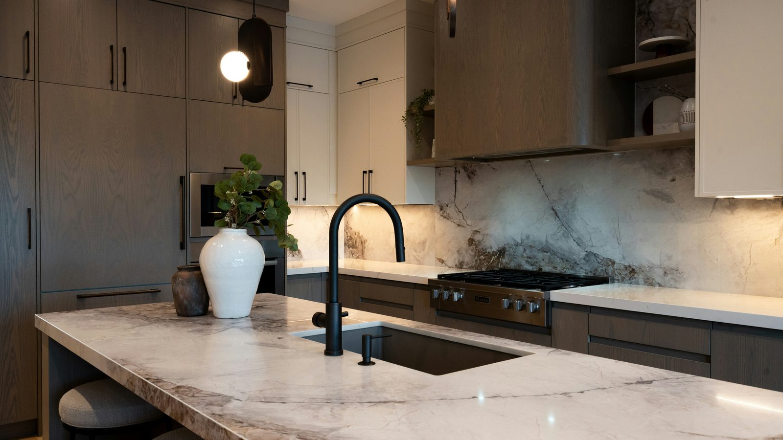 Quartzite island and full-height backsplash in a white oak kitchen
