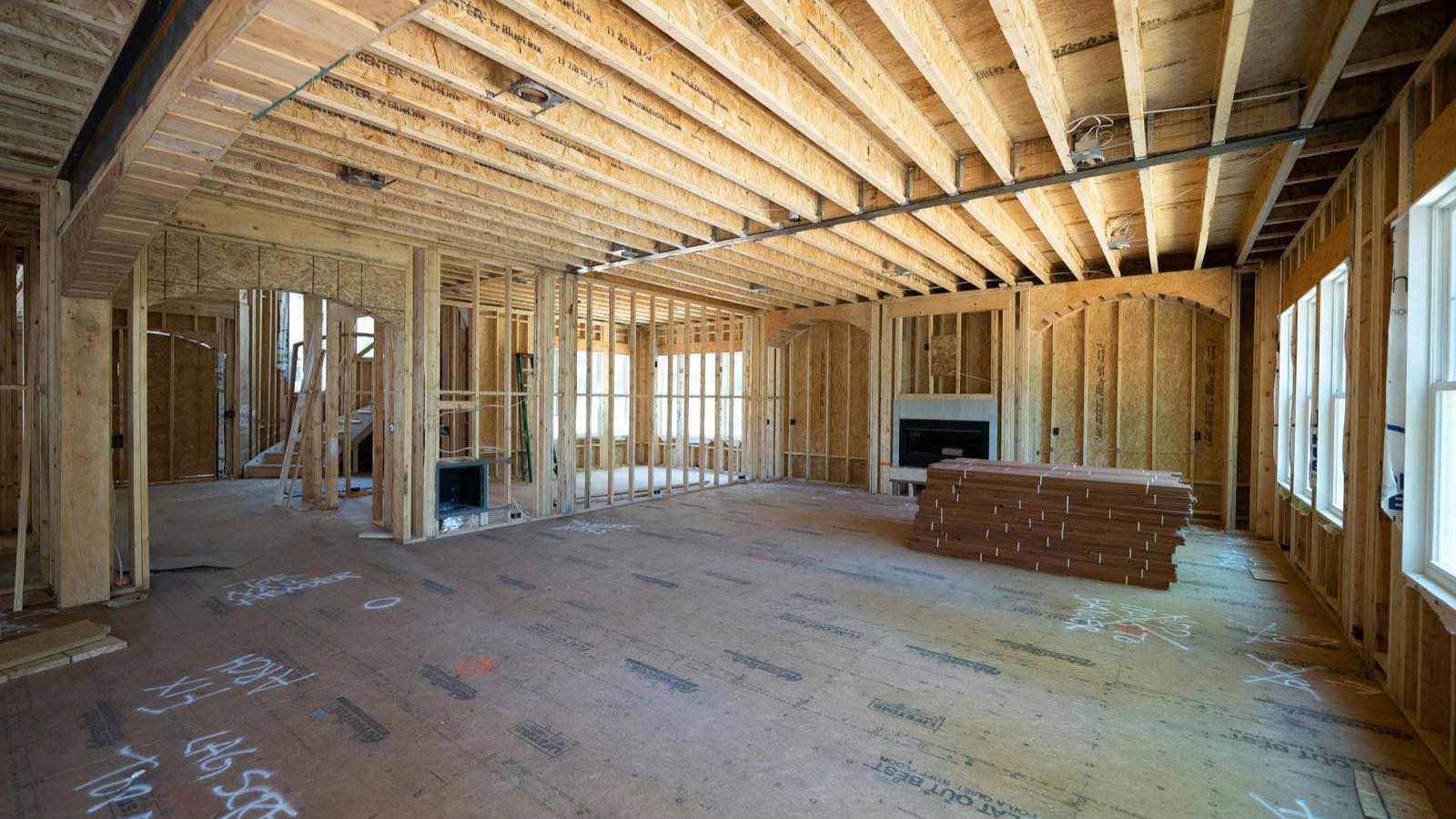 Interior framing of a home under construction with studs and floor joists exposed