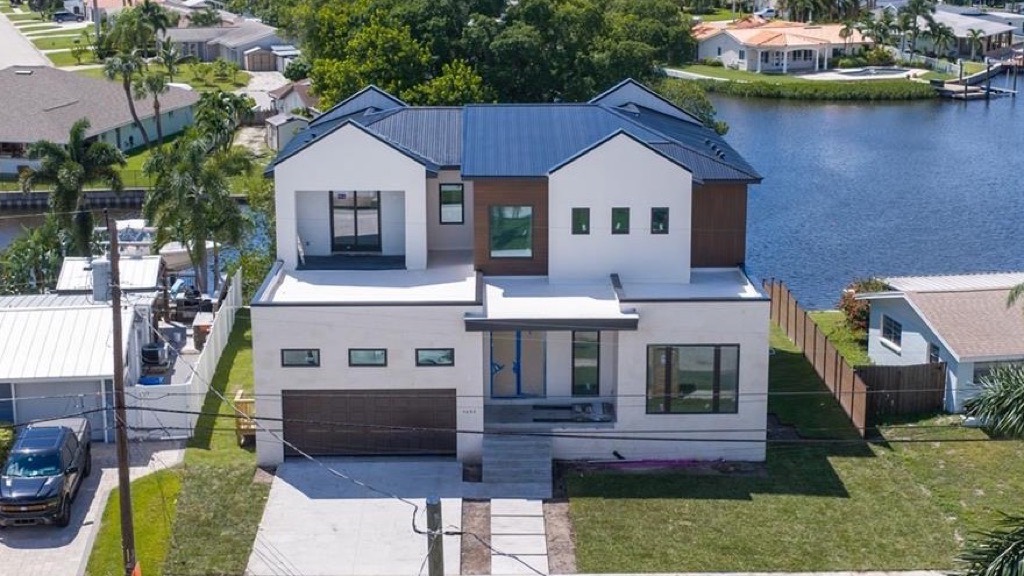 Aerial view of a new two-story white and wood home on a St. Petersburg bayou canal