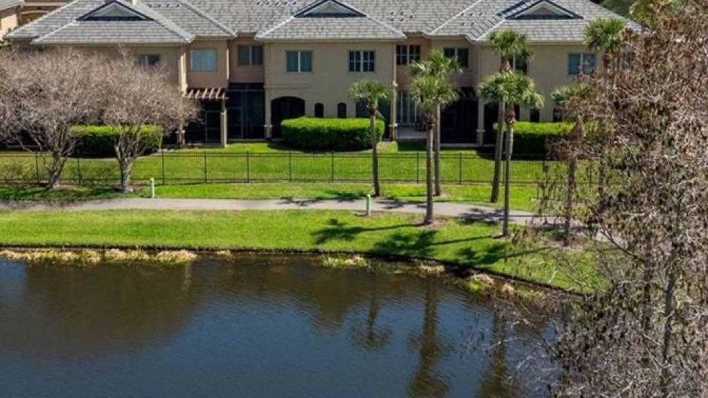 Aerial view of tile-roofed townhomes in a gated Carillon community beside a lake with a fountain
