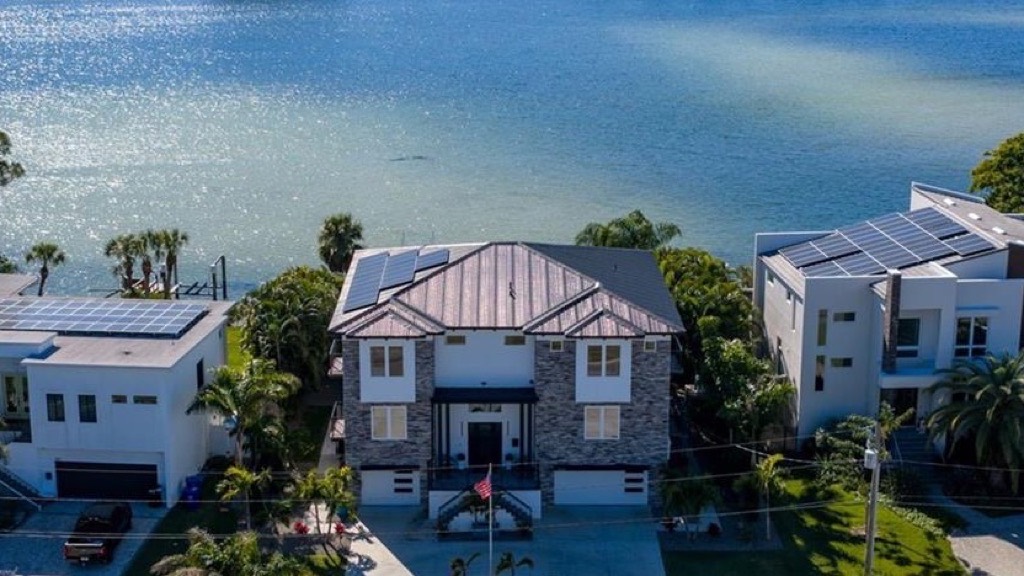 Aerial view of a two-story waterfront home on the open bayou with the downtown St. Petersburg skyline behind it